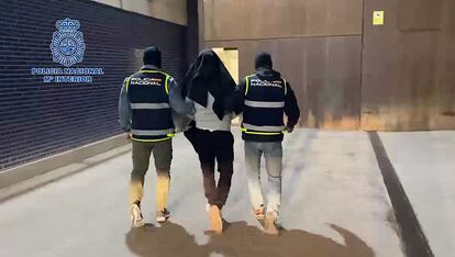 Policías custodio a uno de los 14 detenidos el martes en una captura del vídeo difundido por el Ministerio del Interior.