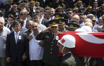 El primer ministro turco, Ahmet Davutoglu, (izquierda) sostiene la mano del padre de un soldado muerto, en su entierro, este viernes en Ankara.