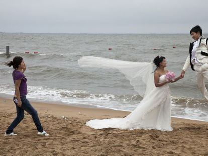 Una pareja de reci&eacute;n casados durante una sesi&oacute;n fotogr&aacute;fica en la playa de Qinhuangdao Beidaihe, al este de China.