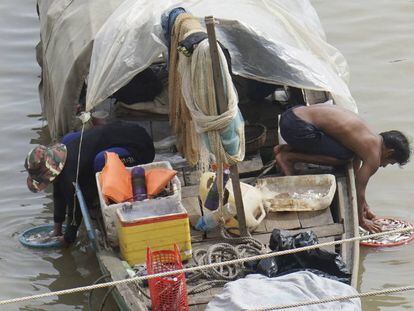 Unos pescadores limpian sus capturas en el río Tonle Sap, en Phnom Penh (Camboya).