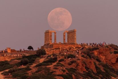 Espectadores observan una luna llena, conocida como la "Luna de las Flores", que se eleva detrás del Templo de Poseidón, cerca de Atenas.