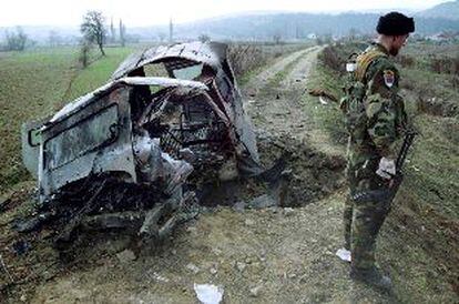 Un policía serbio monta guardia ayer ante los restos del vehículo destruido por una mina en Lucane (Serbia).
