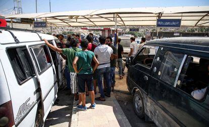 Refugiados sirios, deportados desde Turquía, suben a minibuses en la puerta fronteriza de Bab al-Hawa (Idlib) para dirigirse a diversas partes de Siria.