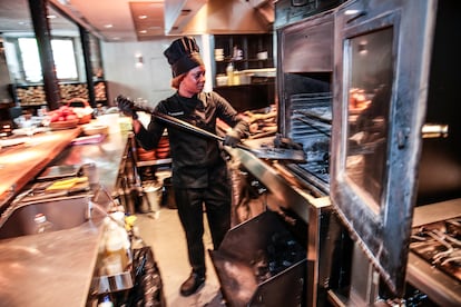 Solange Elguera prepara las brasas para la parrilla antes del servicio, en El Enemigo restaurante. 