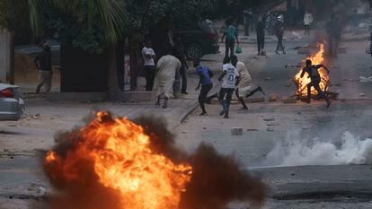 Manifestantes corren en una calle de Dakar mientras la policía les lanza gases lacrimógenos, este jueves 1 de junio.
