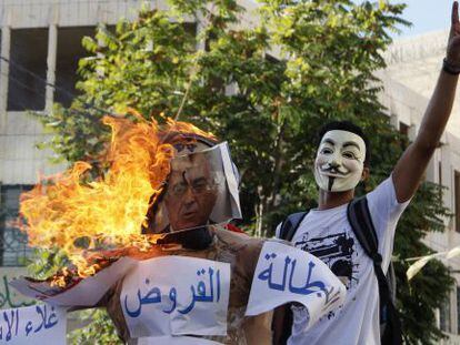 Un manifestante, junto a un figura de Salam Fayad quemada.