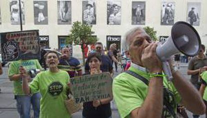 Varios miembros de la Plataforma de Afectados por la Hipoteca (PAH) en la puerta del banco después de que sus compañeros ocuparan hoy la oficina principal del Banco de Santander de Sevilla para protestar contra las hipotecas "abusivas" de la Unión de Crédito Inmobiliario (UCI), una protesta que, según afirman, se ha desarrollado en 50 ciudades.