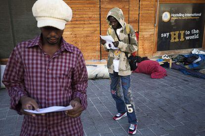 Unos inmigrantes leen las ofertas de los centros de alojamiento que los servicios sociales de París les han ofrecido durante la evacuación del campamento en el que estaban instalados en la calle Pajol de la capital francesa.