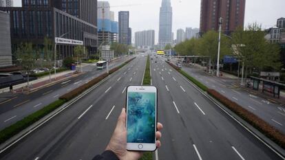 Una persona sostene un teléfono móvil frente a una carretera casi vacía en Wuhan.