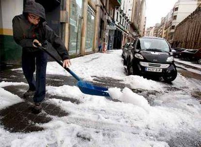 Un vecino de Santander limpia la calle tras la fuerte tormenta de granizo caída esta mañana