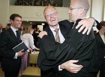 Los abogados Coenen (izquierda) y Lemstra se abrazan tras el triunfo del grupo de accionistas VEB.