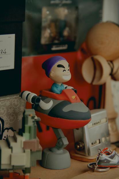 A Staple doll aboard Nikes, in his office.