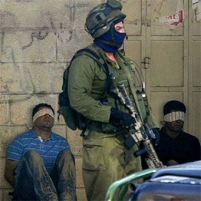 Un soldado israelí custodia a dos palestinos capturados durante una incursión en Ramala, en Cisjordania.