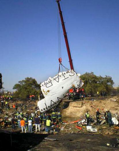 Una grúa levanta parte del fuselaje de la aeronave en el lugar del accidente del avión de Spanair.