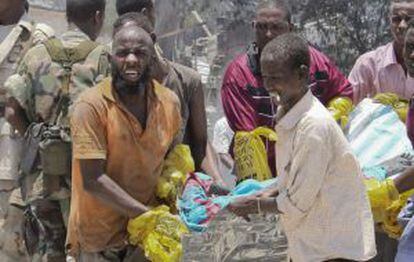 Un grupo de somalíes carga el cadáver de una de las víctimas de la explosión de un coche cargado de explosivos en Mogadiscio.
