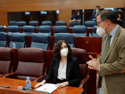 El diputado del PP Alfonso Carlos Serrano habla con Isabel Díaz Ayuso, durante el pleno de este jueves en la Asamblea de Madrid.