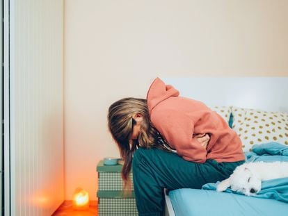 Una chica acurrucada en la cama de dolor.