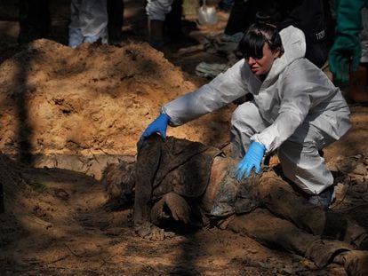 Una forense examina el cuerpo de un hombre para comprobar, entre otras cosas, si ha sufrido torturas, durante la exhumación de decenas de cadáveres en Izium, a mediados de septiembre.