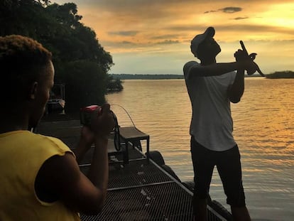 Dos turistas se hacen fotos durante el atardecer a orillas del r&iacute;o Chobe, frontera natural entre Botsuana y Namibia.