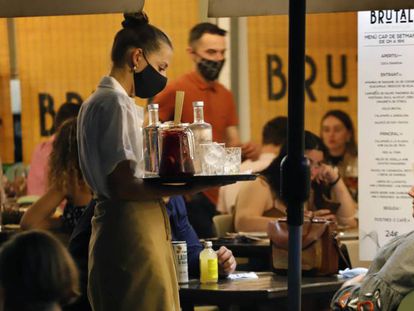 Una camarera sirve una bebida a un cliente en una terraza 