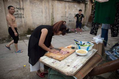 Pero ahora, la presión demográfica hace que Pekín prefiera que desde la provincia lleguen trabajadores urbanos y con alguna titulación. En la foto, una mujer cocina en una de las calles del vecindario.