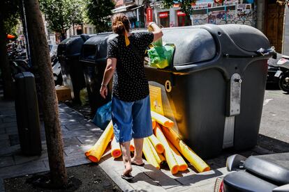 Una joven intenta meter una bolsa en un contenedor.