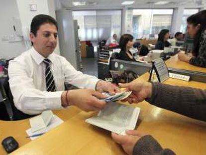 Un empleado de una sucursal del Banco Laiki entrega el dinero retirado por uno de sus clientes en Nicosia (Chipre).