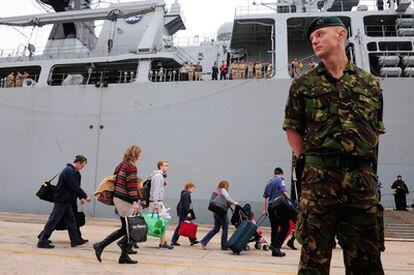 Un marino de la Armada británica mira a los pasajeros mientras suben al buque HMS Albion en Santander. Londres ha movilizado a su Armada para transportar a los británicos que se han quedado retenido en Santander por el cierre del espacio aéreo.