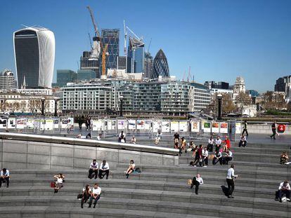 Londinenses relaj&aacute;ndose al sol cerca del Ayuntamiento, con la City al fondo.