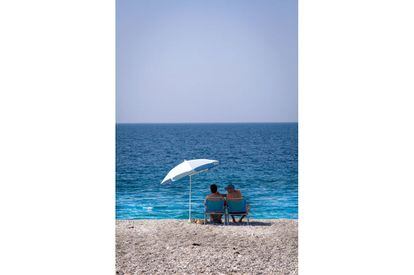 Una pareja descansa bajo una sombrilla en la playa de Calahonda, en la Costa Tropical de Granada.