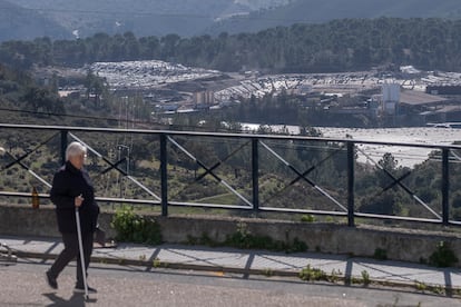 Una señora pasea en la barriada del Ventoso de Nerva, con el vertedero al fondo. 