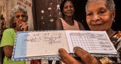 Una se&ntilde;ora muestra su libreta de racionamiento en Santiago de Cuba.