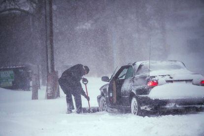 Un hombre quita la nieve de las ruedas de su vehículo en Bellport, en el estado de Nueva York, el 4 de enero de 2018.