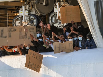 Migrantes retenidos en el muelle de Catania (Italia) muestran pancartas pidiendo ayuda, este lunes.