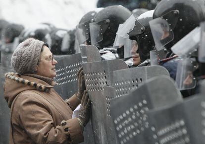 Una mujer se dirije a los miembros de la policía que hacían fila protegidos con castcos y escudos, durante los enfentamientos con manifestantes pro-europeos en Kiev.