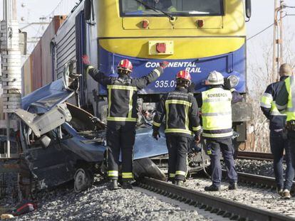 Bomberos trabajan en la zona del suceso. En vídeo, un cercanías arrolla una furgoneta y mueren sus dos ocupantes.