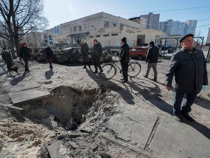 Personas observan el cráter de un proyectil después de un bombardeo en una zona residencial de Kiev, Ucrania, en febrero de 2022.