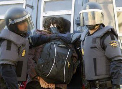 La policía custodia a un detenido durante los incidentes de hoy en Valencia.