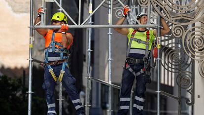 Dos trabajadores montan un andamio en una obra en la ciudad de Valencia