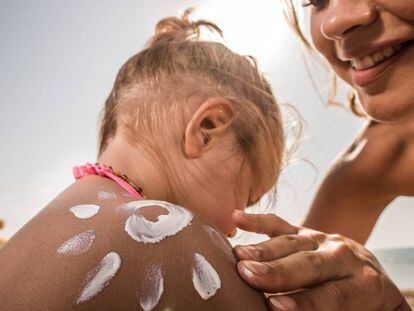 Una madre echa crema solar a su hija.