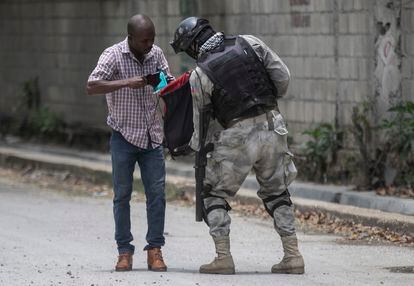 Un oficial de policía registra la bolsa de un residente durante una operación antipandillas en Croix-des-Missions, al norte de Puerto Príncipe, el jueves 28 de abril de 2022. 