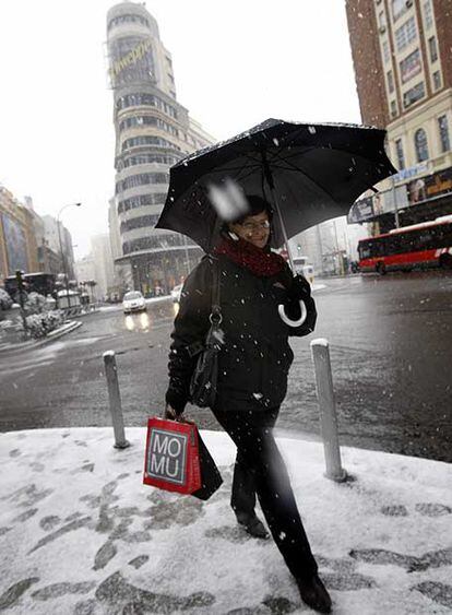 Una mujer camina con precaución por la Gran Vía bajo la intensa nevada.