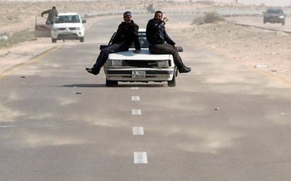 Rebeldes libios avanzan subidos a un coche, cerca de la carretera que une Bengasi y Ajdabiya.