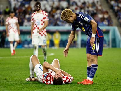Borna Barisic, de Croacia, tendido en el suelo mientras el japonés Ritsu Doan le presta su ayuda. 