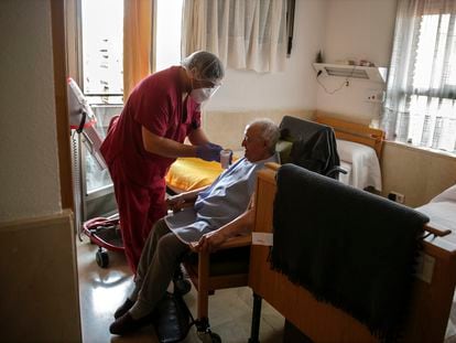 Un empleado le da líquido a un hombre mayor en una de las habitaciones en la Residencia de ancianos Santa María de Montecarmelo en Madrid, el pasado abril.
