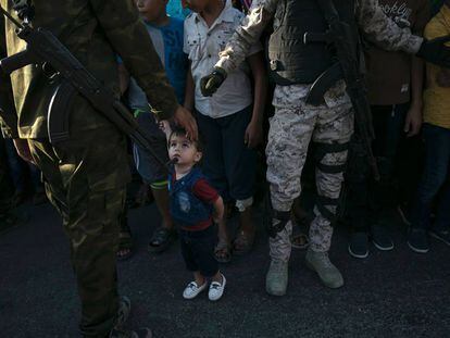 Un niño mira a un miembro de las Brigadas de Al Qassam, rama militar de Hamás, durante un desfile antiisraelí.