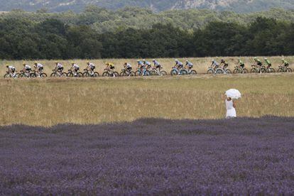 Una mujer con paraguas observa a los ciclistas que compiten en el Tour de Francia durante la décimonovena etapa entre Embrun y Salon-de-Provence (Francia).