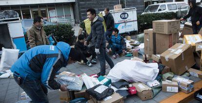 Varios repartidores clasifican paquetes en una calle de Pekín.