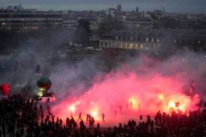 Los manifestantes caminan entre el humo de las bengalas al final de la manifestación contra los planes para retrasar la edad de jubilación en París.