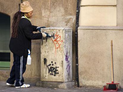 Una trabajadora limpia la calle contratada por Barcelona Activa dentro de uno de los programas sociales